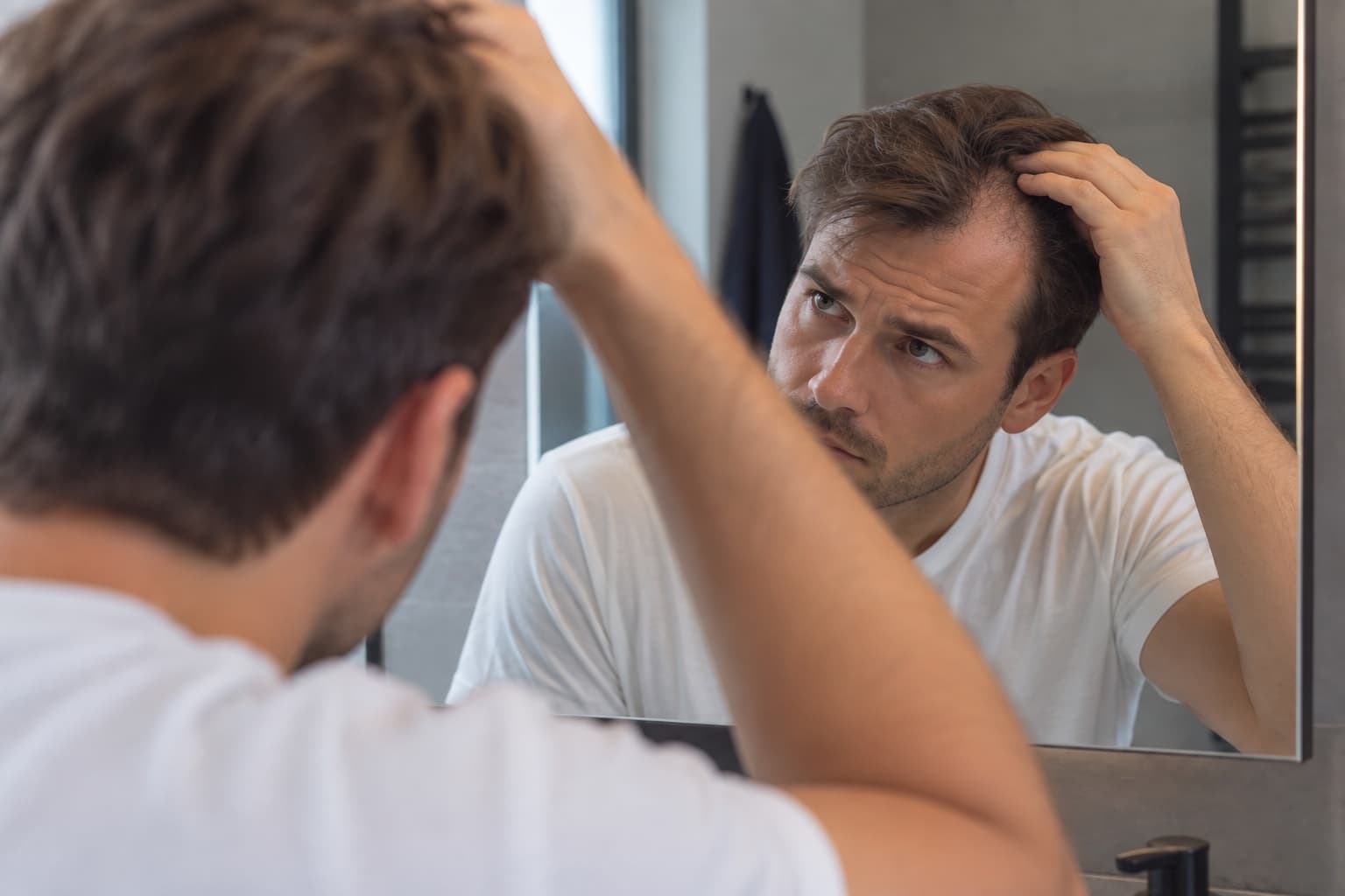 Man bekijkt zijn haarlijn in de spiegel